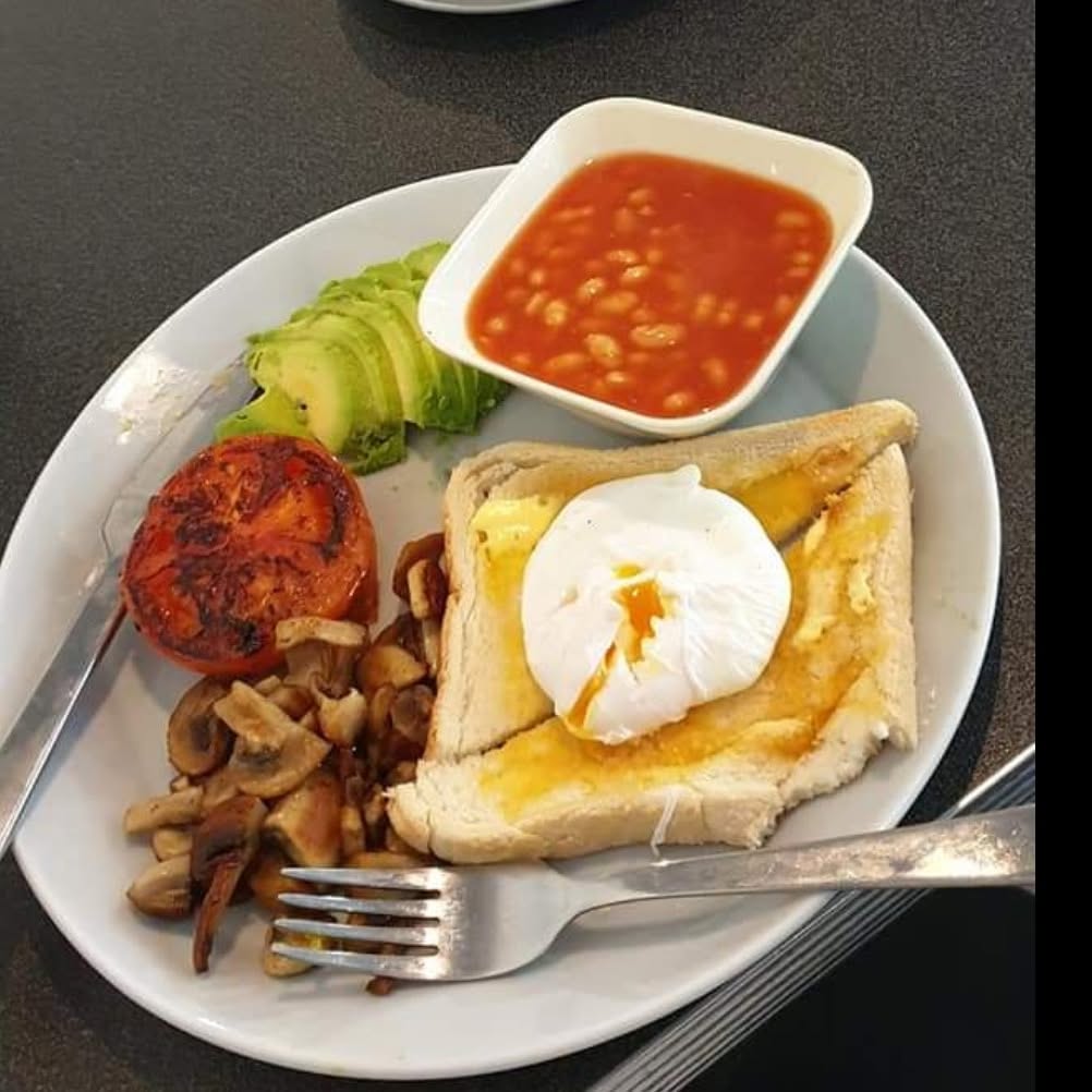 A breakfast plate with toast, an egg, beans, avocado, mushrooms and tomato in a café photograph from February 2019.